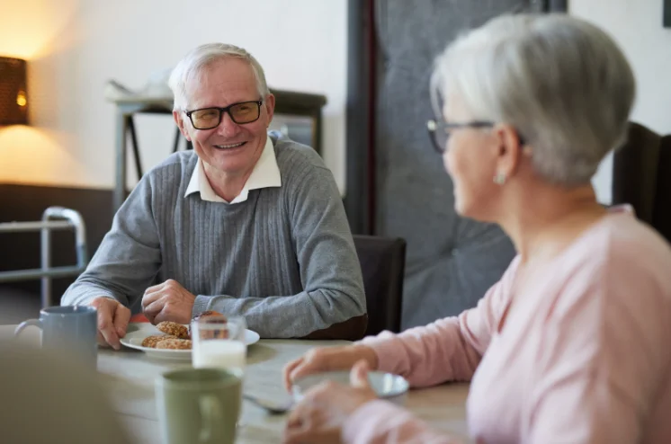 Photo of an elderly couple seated around a breakfast table smiling at one another
